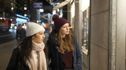 Naklejka premium Two girls on a shopping trip in New York walk along shop windows