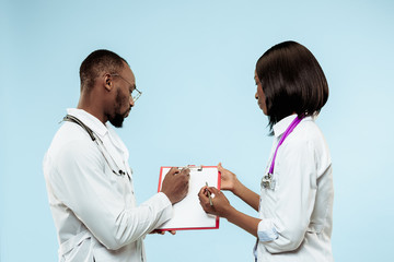 The female and male smiling happy afro american doctors on blue background at studio.The clinic, medical, nurse, health, healthcare, hospital, care, job, professional concept