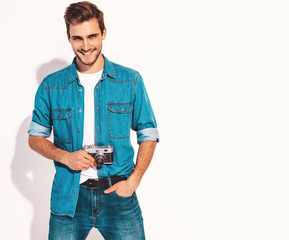 Portrait of handsome smiling man wearing summer hipster jeans clothes. Model male taking picture on old vintage photo camera. Isolated on white