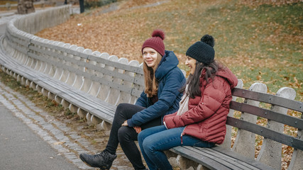 Two girls in Central Park New York sit on a bench to relax
