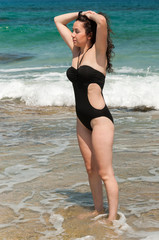 Girl in a black swimsuit standing in the coastal waves