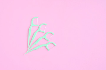 Plastic green toothpicks with dental floss for personal daily teeth hygiene on pink background....