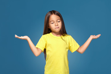 Surprised girl with spread arms on blue background