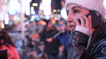 Young woman takes a phone call on Times Square by night