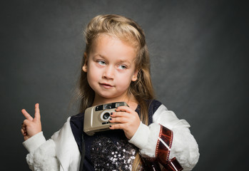 Little beautiful girl with an old camera. Young photographer