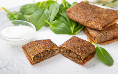 Russian pancakes with meat with spinach leaves and sour cream