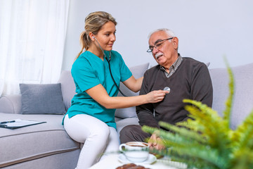 Taking care of health. Selective focus on a serene retired gentleman sitting on a sofa while a female nurse using her stethoscope and listening to his lungs.
