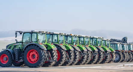 Ausstellung / neue Traktoren aufgestellt nebeneinander in einer Reihe