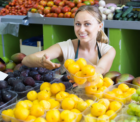 Obraz premium Portrait of friendly woman selling ripe fresh plums