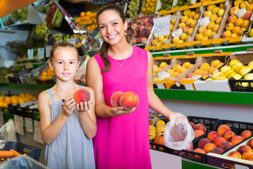 Fototapeta premium woman with girl buying peaches