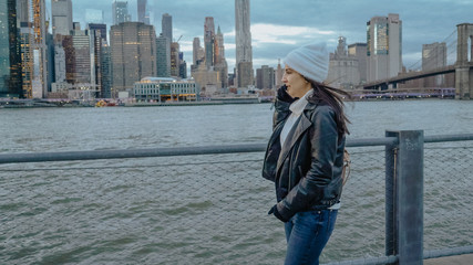 Young woman walks along the wonderful skyline of Manhattan in the evening