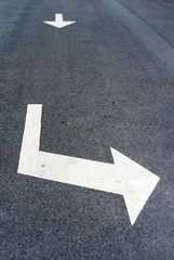 Arrows with direction signs on a asphalted street - image