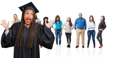 Young graduated black woman wearing braids screaming happy, surprised by an offer or a promotion, gaping, jumping and proud