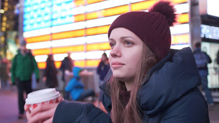 Young woman drinks a cup of coffee in the streets of New York