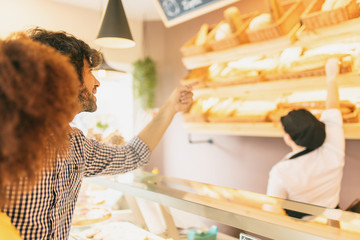 Young modern couple at bakery, choosing a loaf of bread.