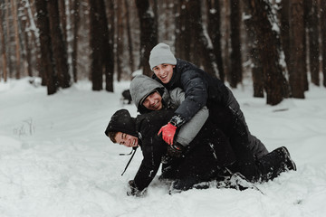 Fototapeta na wymiar Happy friends in winterwear playing with snow in park. Ukraine 2019