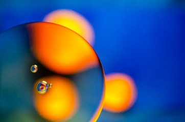 round yellow tangerines through oil stain on blue background