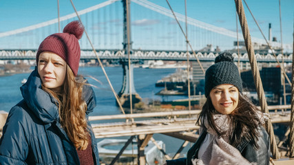 Two girls walk over the famous Brooklyn Bridge in New York