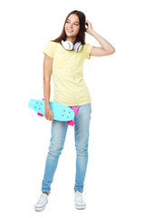 Young girl with skateboard and headphones on white background