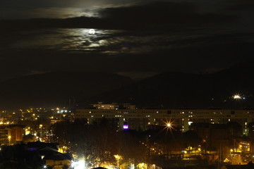 Fototapeta na wymiar Moon rising behind the clouds in urban landscape, Terni, Umbria, Italia