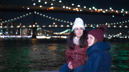 Two girls explore New York by night here at Brooklyn Bridge