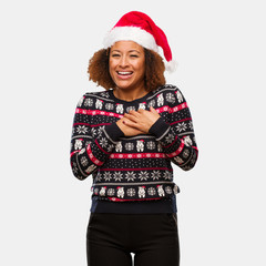 Young black woman in a trendy christmas sweater with print doing a romantic gesture