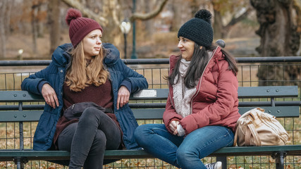Two girls sit on a bench on Central Park enjoying their time in New York