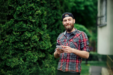 Image of handsome young bearded male with a smartphone in hands looking forward