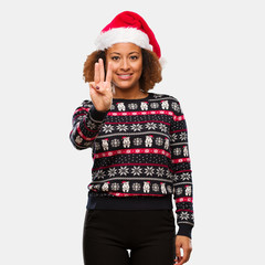 Young black woman in a trendy christmas sweater with print showing number three