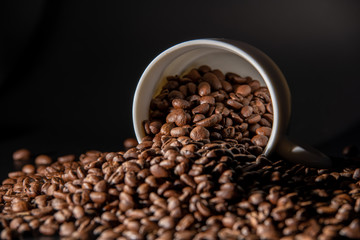 white cups with a pattern and grains of coffee on a black background