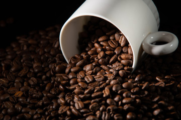 white cups with a pattern and grains of coffee on a black background