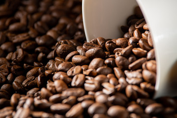 white cups with a pattern and grains of coffee on a black background