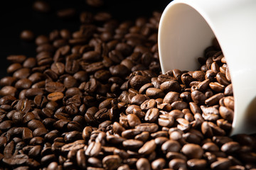 white cups with a pattern and grains of coffee on a black background