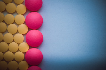 Pink and yellow pills in a row on a blue background.