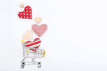 Shopping cart with fabric hearts on white wooden table