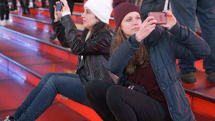 Two girls at Times Square by night sit on the famous red steps