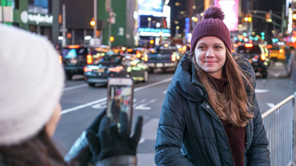 Two girls in New York take photos at Times Square
