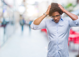 Afro american business man wearing glasses over isolated background suffering from headache desperate and stressed because pain and migraine. Hands on head.