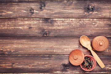 Wooden kitchen spoon and bowl with pepper spice on brown table