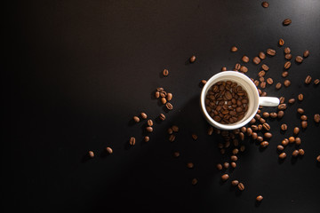 white cups with a pattern and grains of coffee on a black background