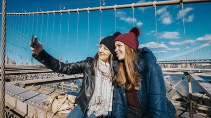 Two young women take a selfie on Brooklyn Bridge New York
