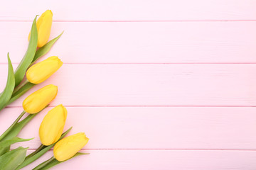 Bouquet of yellow tulips on pink wooden table