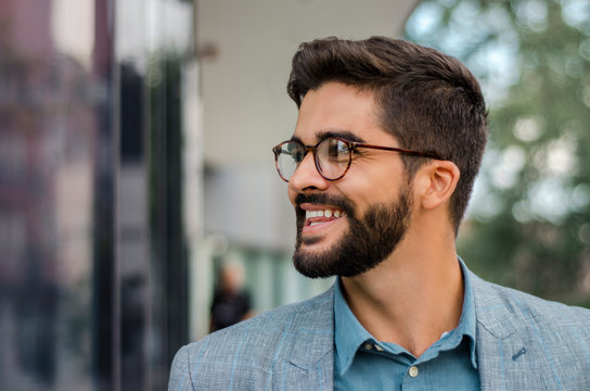 Closeup outdoors portrait of handsome dark hair bearded man with stylish eyeglasses 