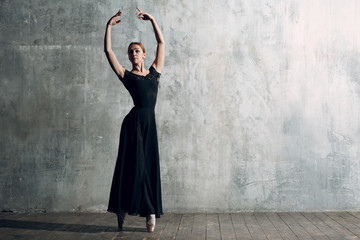 Ballerina female. Young beautiful woman ballet dancer, dressed in professional outfit, pointe shoes and black dress.