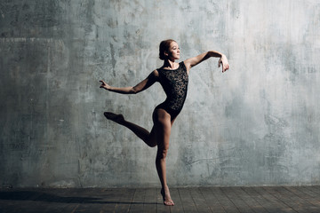 Fototapeta na wymiar Ballerina female. Young beautiful woman ballet dancer, dressed in professional outfit, pointe shoes and black body.