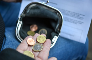Ältere Frau zählt Kleingeld und hält Rentenbescheid in der Hand