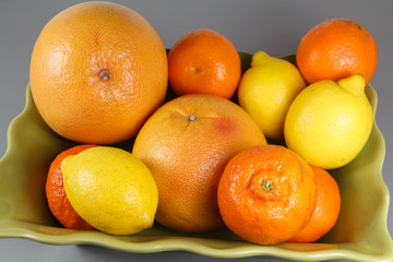 Dish with clementines, grapefruits and lemons on a table