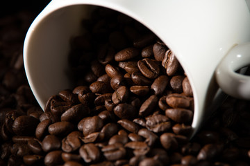 white cups with a pattern and grains of coffee on a black background