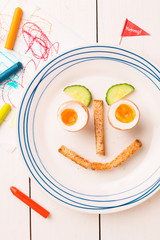 Funny face - kid's breakfast - eggs, toasts and cucumber
