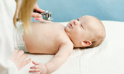 small child, child, lies in the doctor's office, and the doctor listens to the lungs, heart. The...